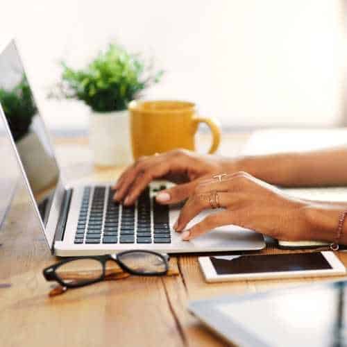 Organised workspace with a laptop showing a blurred Zoom workshop screen, coffee mug featuring the Digital Coach for Coaches logo, notepad, pen, and lightbulb overlay symbolising AI and SEO visibility training.