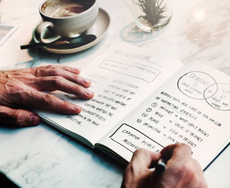 how-to-close-the-expertise-to-enquiry-gap Notepad with a a businessman writing out some marketing strategy questions